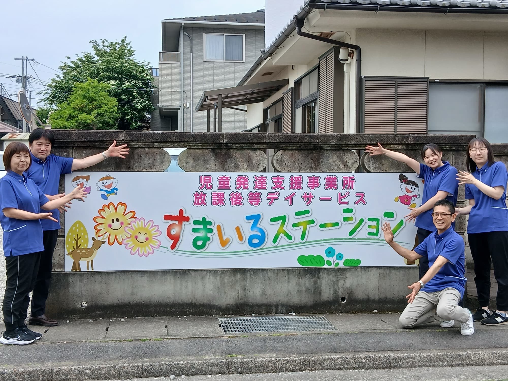 施設前に並ぶスタッフと看板